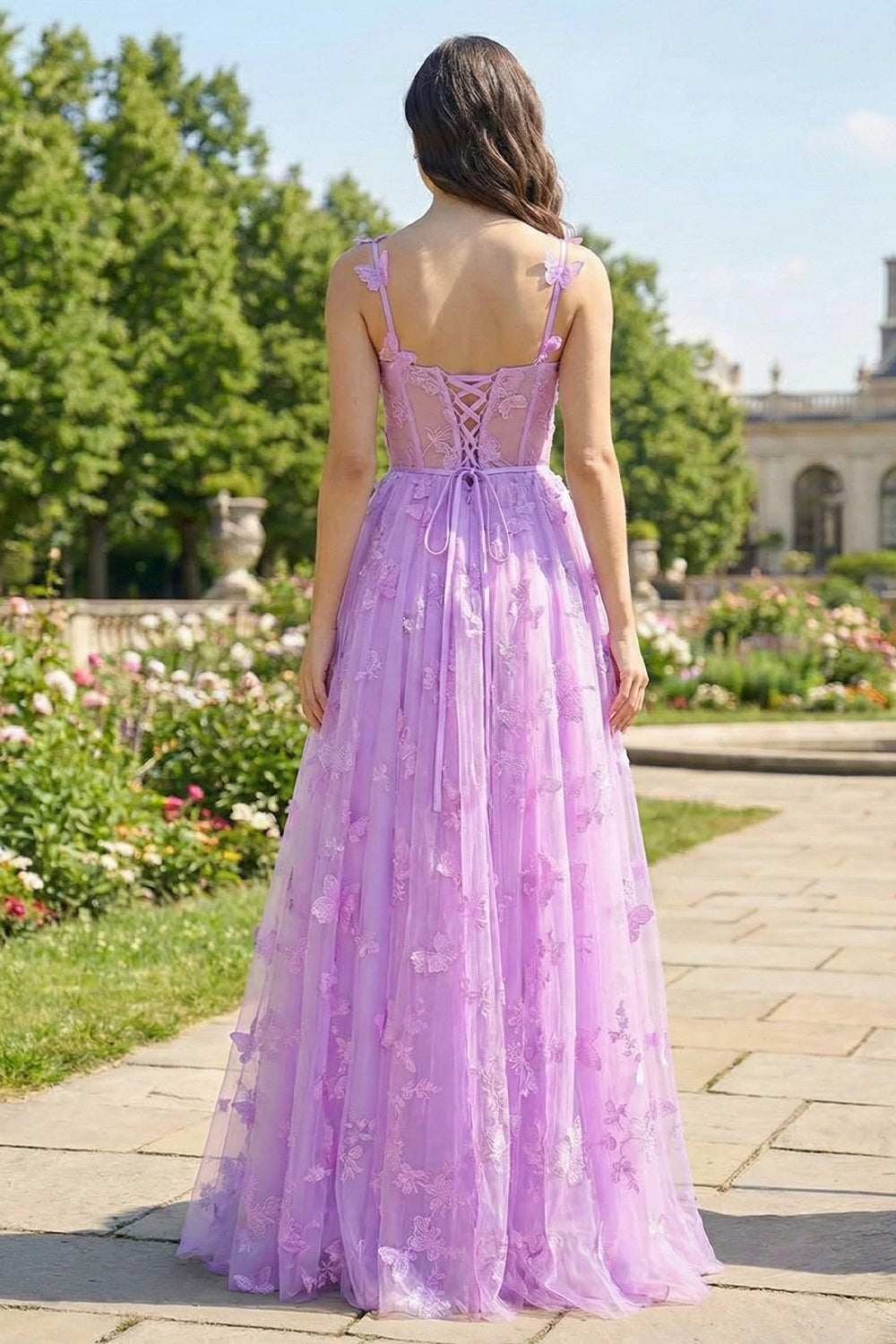 Back view of Sevoba lavender fairy evening gown showing a lace-up corset back and butterfly details on the skirt, garden background.