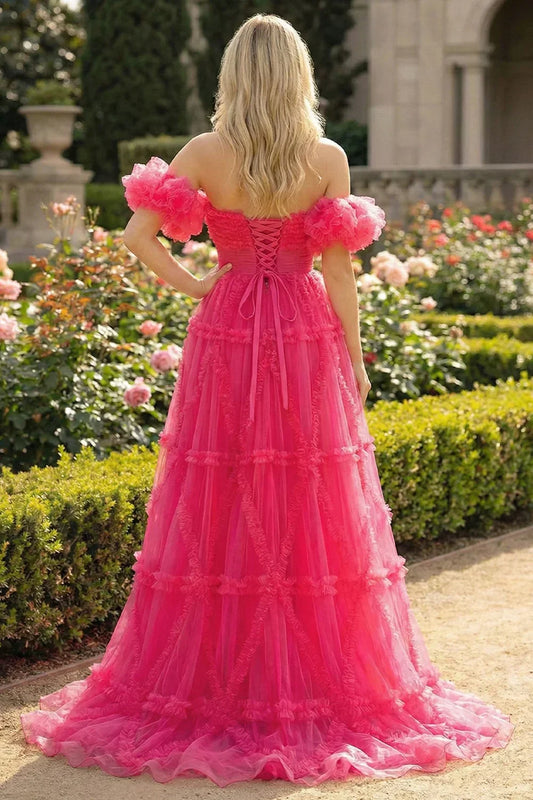 Back view of Sevoba fuchsia pink tulle ball gown showing a lace-up corset back and voluminous ruffled skirt, garden background