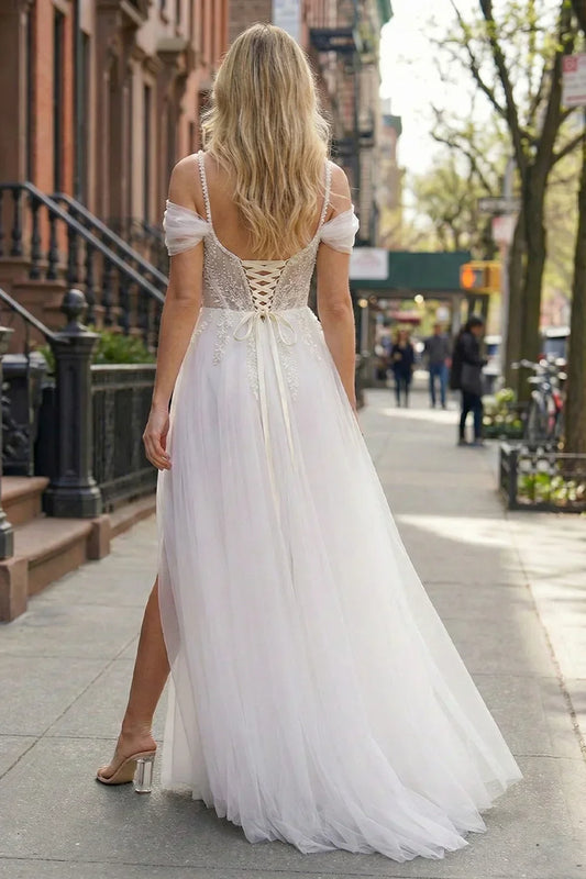 Back view of Sevoba white lace-up corset evening gown showing beaded straps and flowy tulle skirt, street background