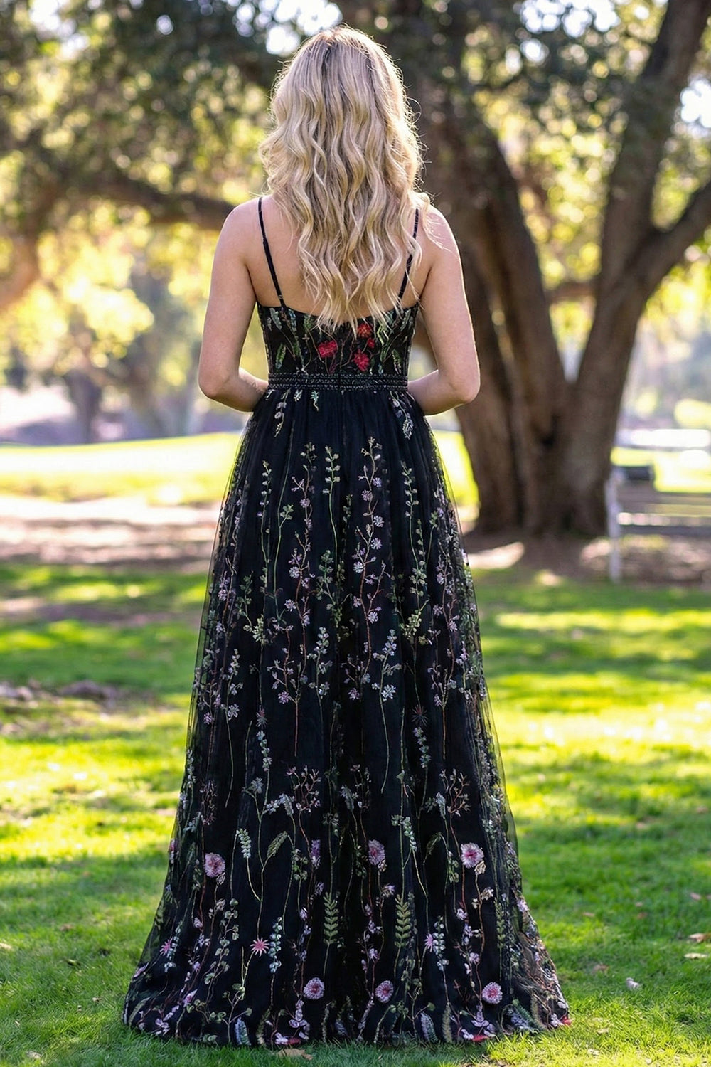 Back view of Sevoba black floral embroidered evening gown showing a zipper closure and floor-length embroidered skirt, park background