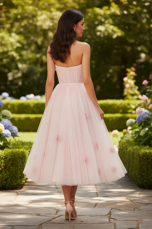 Back view of Sevoba pink tulle midi dress showing a zipper closure and scattered flower details on the skirt, outdoor garden setting
