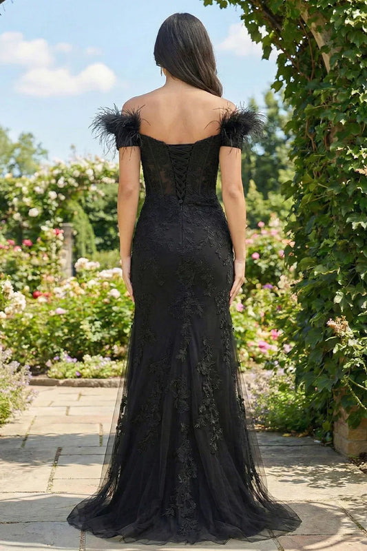 Back view of Sevoba black feather strap lace evening gown showing a lace-up corset back and floor-length tulle skirt, garden background