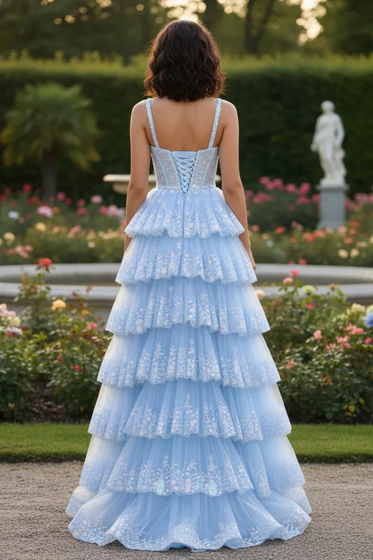Back view of Sevoba light blue floral embroidered prom dress showing a lace-up corset back and tiered tulle skirt, garden background