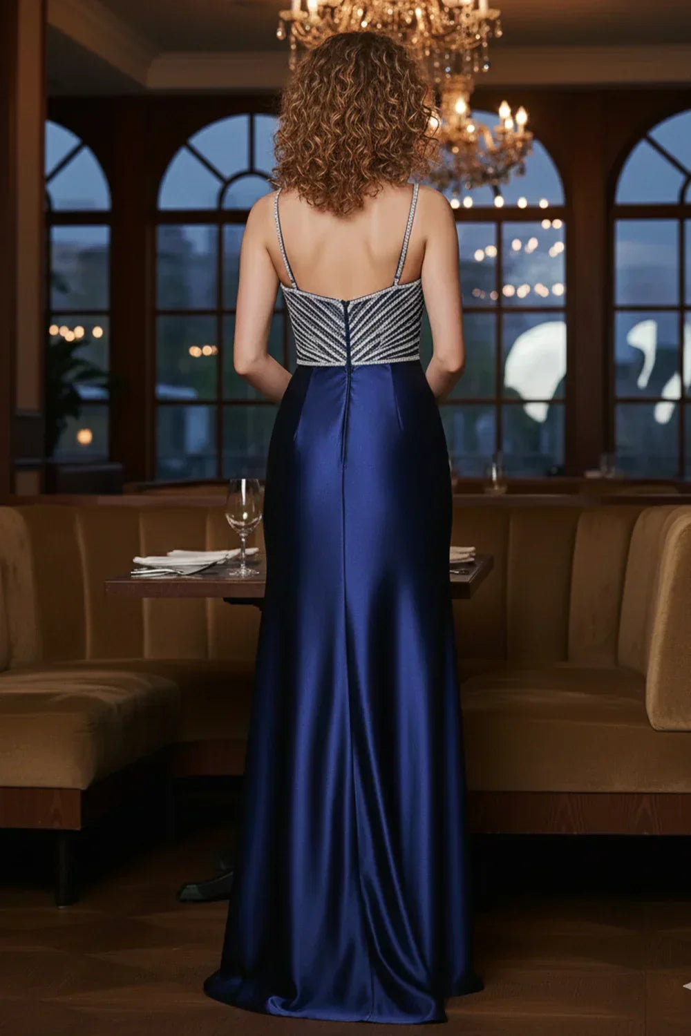 Sevoba navy V-neck beaded bodice satin floor-length prom dress, back view in chandelier-lit lounge