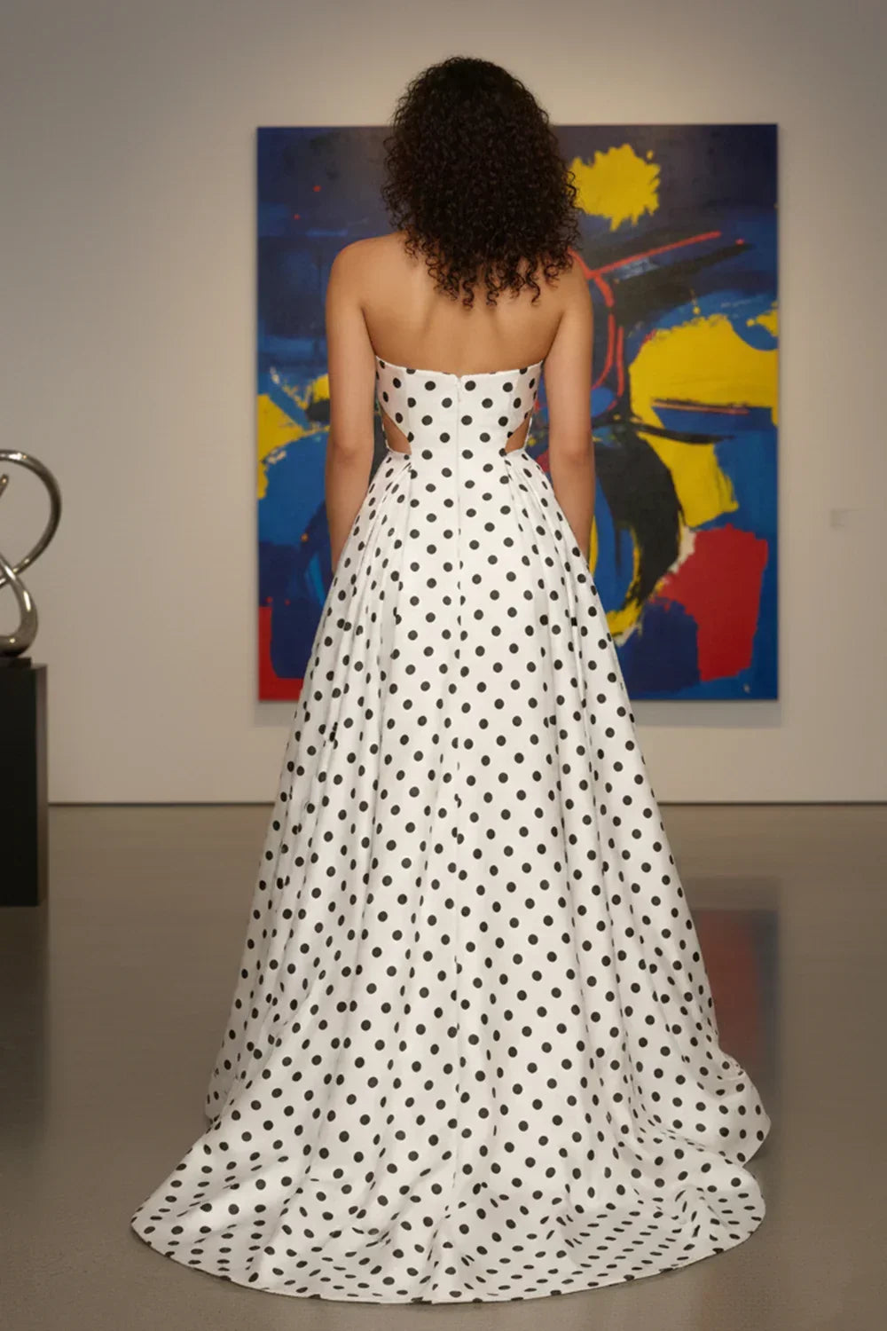 Woman in a strapless white A-line prom dress with black polka dots and pockets