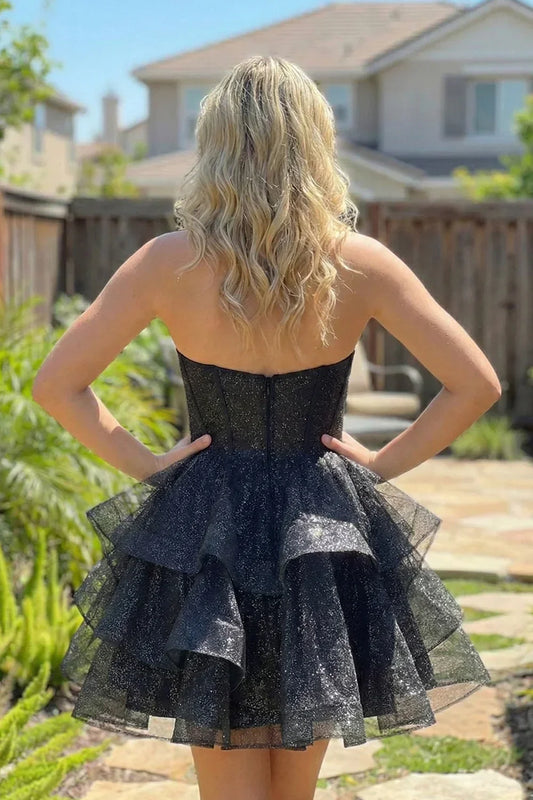 Woman wearing a strapless black sparkle tulle short homecoming dress with ruffles outdoors