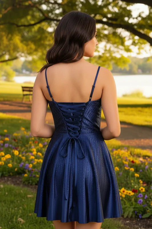 Woman in a navy blue A-line beaded homecoming dress with spaghetti straps outdoors