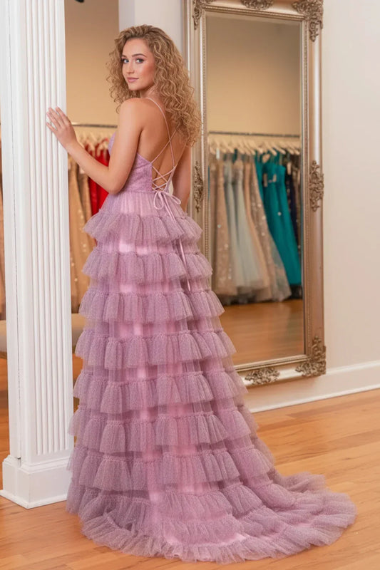 Woman in a lilac ruffled tulle prom dress with spaghetti straps and open back, standing in a boutique.