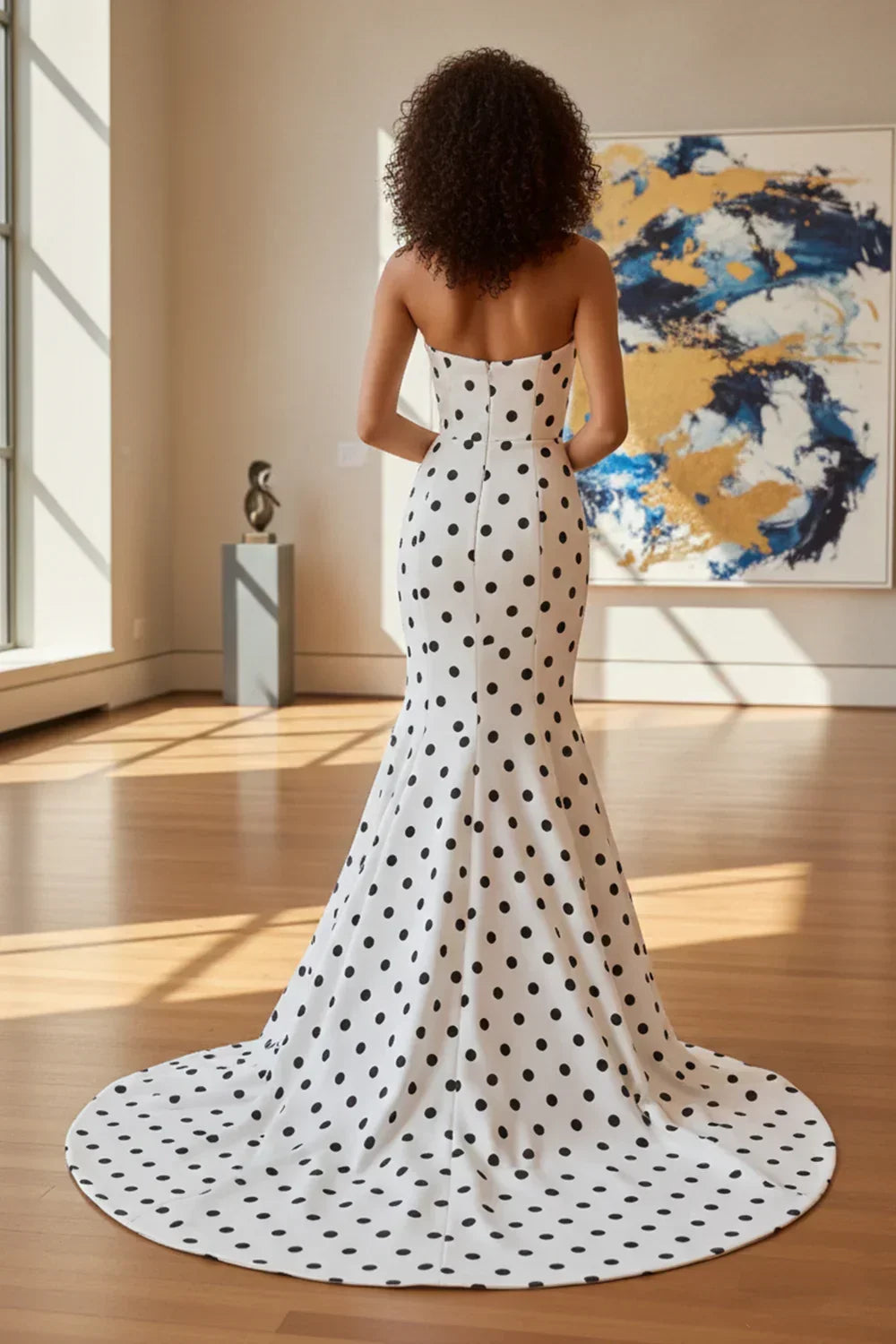 Woman in a strapless white polka dot mermaid prom dress with long train, elegant indoor setting