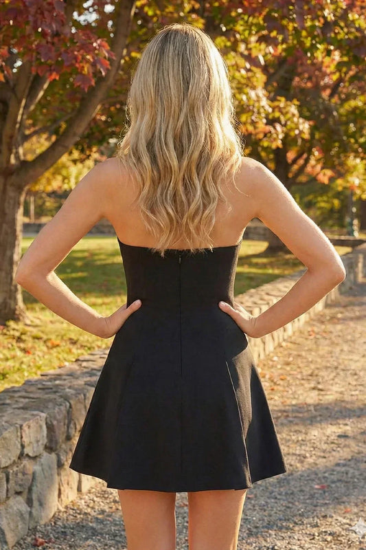 Back view of a woman in a black strapless satin short dress outdoors in autumn.