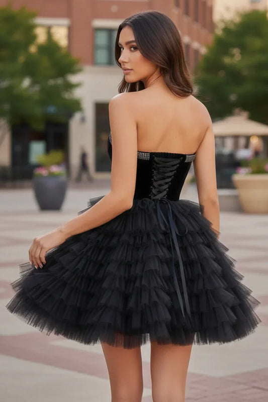 Woman wearing a strapless black velvet and tulle tiered homecoming dress with beaded trim