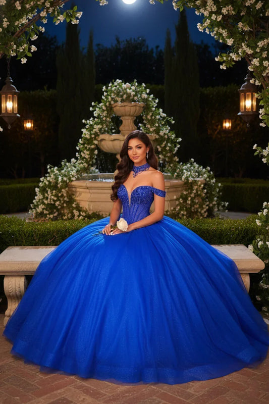 Woman in royal blue off-the-shoulder ball gown with lace detail, sitting outdoors at night