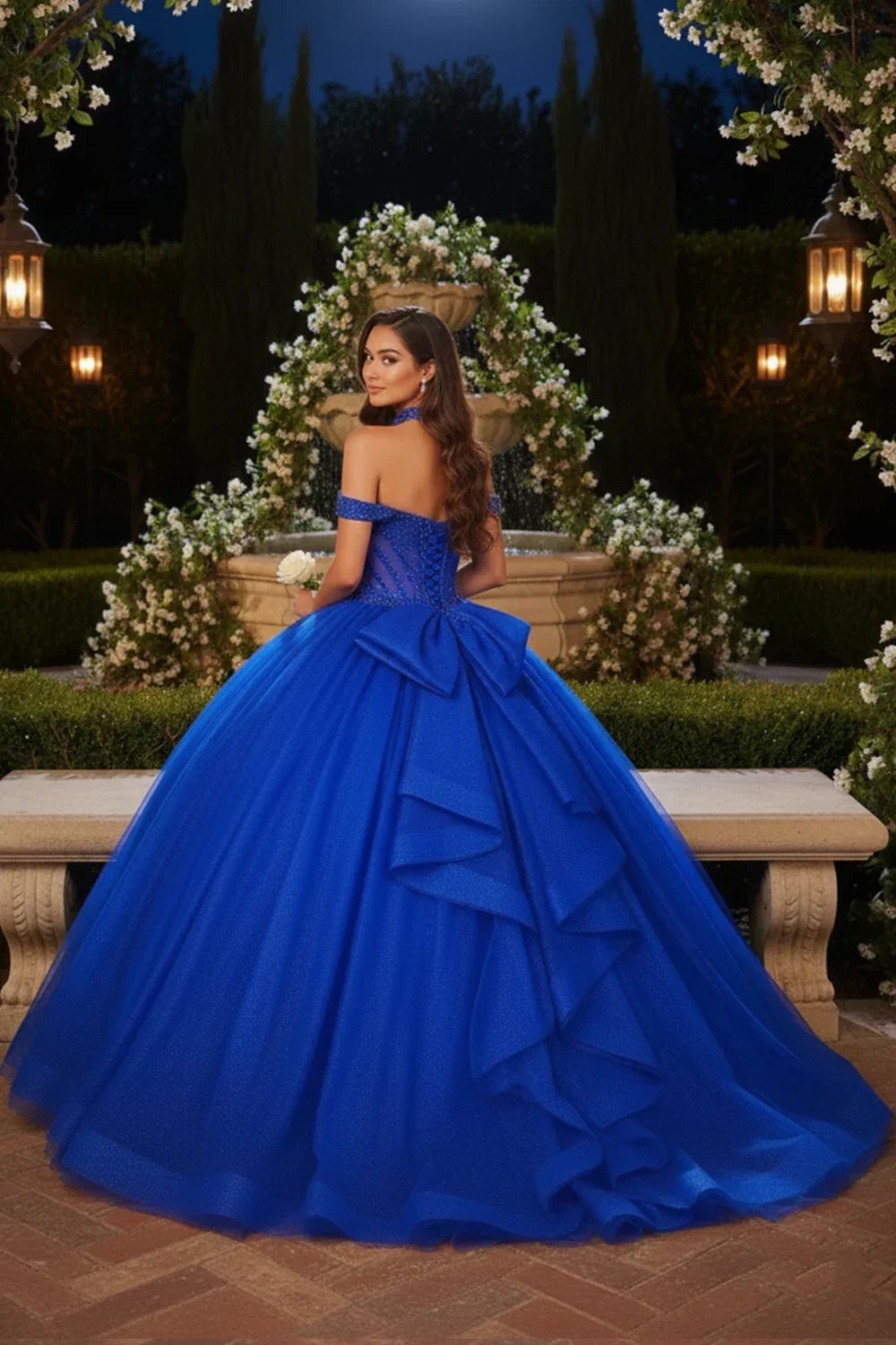 Woman in royal blue off-the-shoulder ball gown with lace and bow detail, garden backdrop