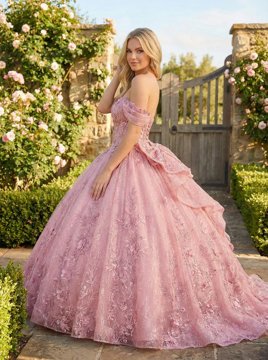 Woman in a pink embroidered ball gown with cold-shoulder sleeves standing in a garden