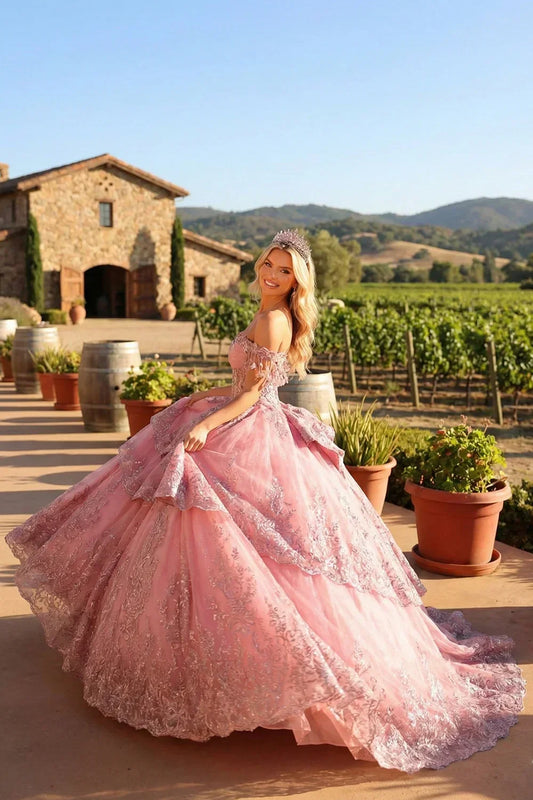 Woman in a pink floral appliqué ball gown with cold shoulder design and tiara outdoors