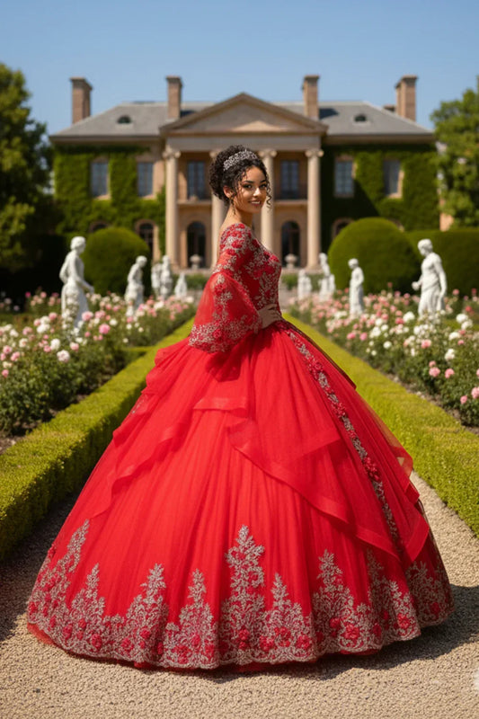 Woman in red ruffled tulle ball gown with silver beading standing in a formal garden