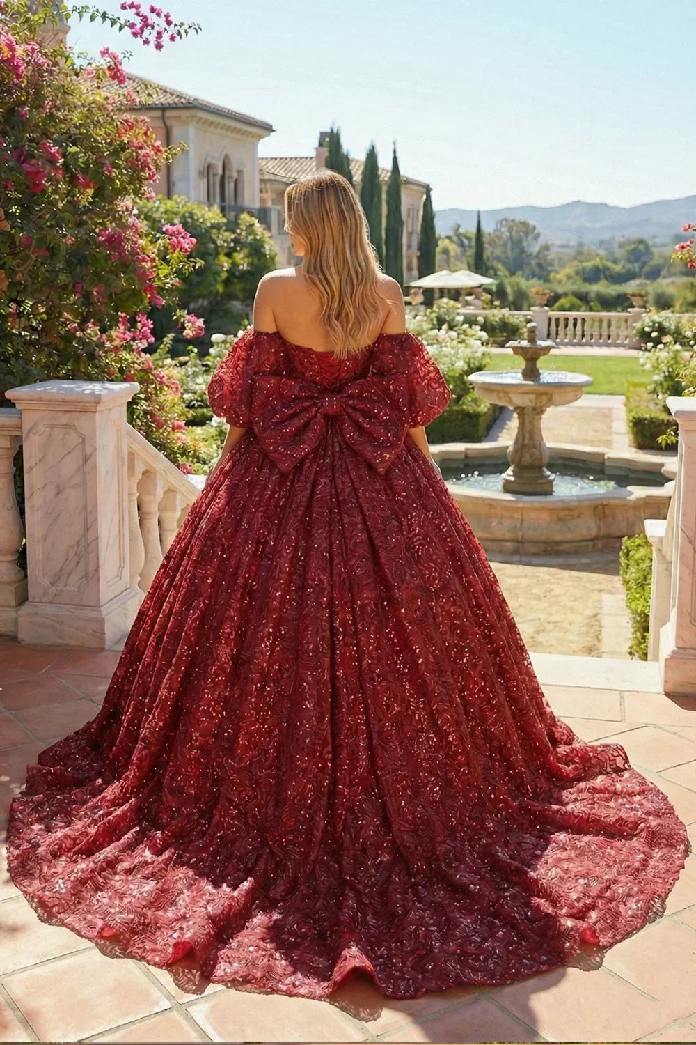 Woman in a red embroidered ball gown with large bow, standing in a garden courtyard