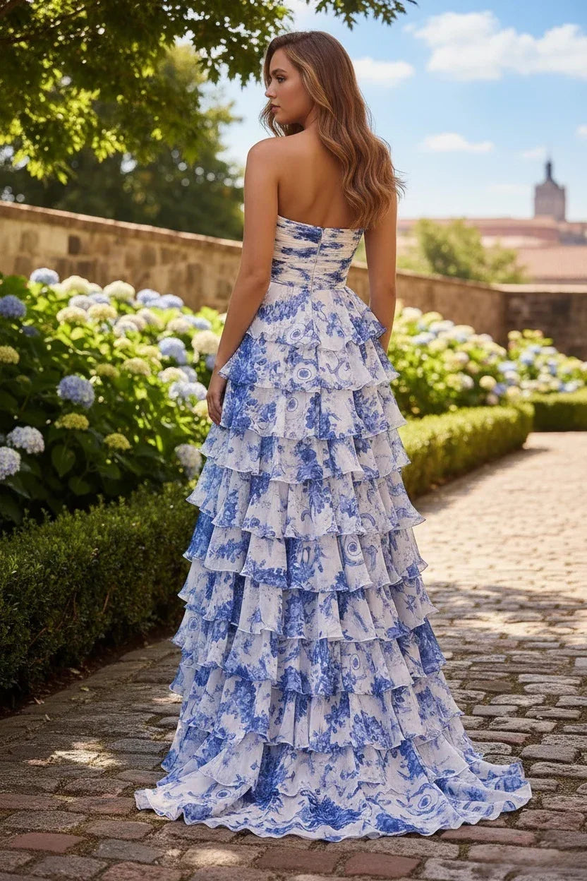 Woman in strapless blue and white tiered floral prom dress outdoors on a garden path