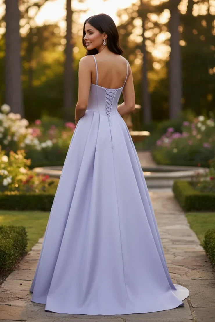 Woman in a lilac satin A-line prom dress with spaghetti straps and lace-up back, outdoors.
