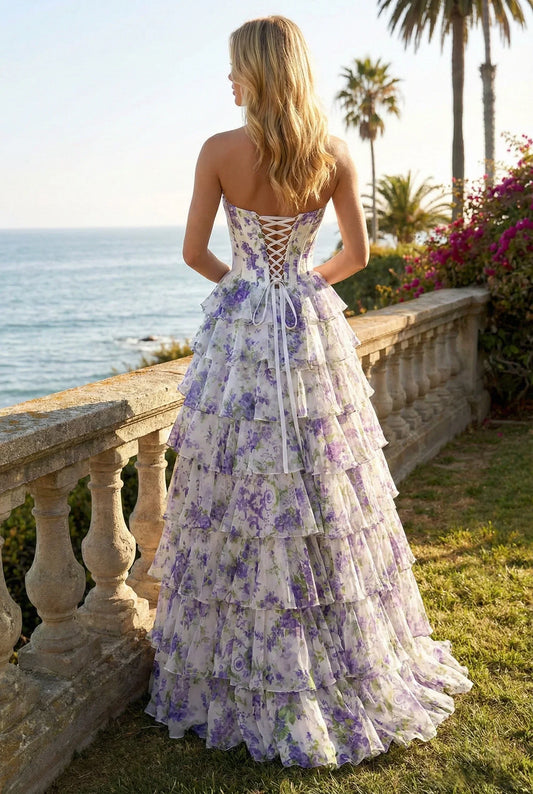 Woman in strapless ruffled floral A-line prom dress with tiered layers, outdoor garden setting