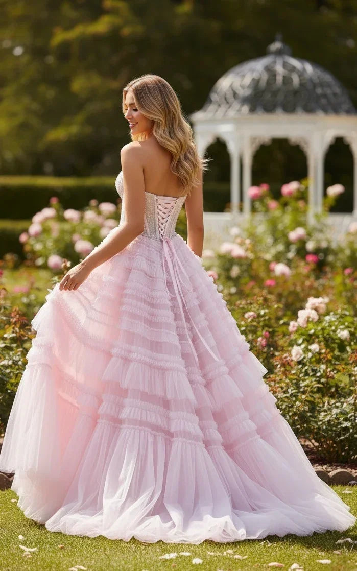 Woman in pink strapless ruffled tulle prom dress with beading, outdoors in a garden.