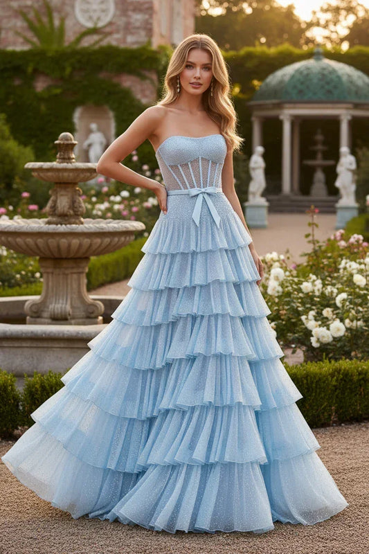 Woman in light blue strapless A-line beaded prom dress with ruffle tiers and bow outdoors