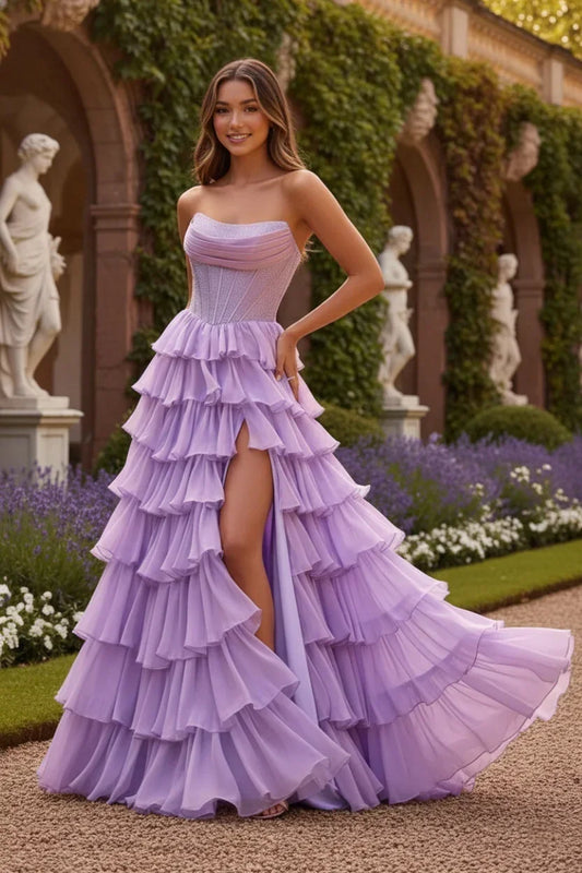 Woman in a lilac strapless ruffled chiffon prom dress with a high slit, posing outdoors.