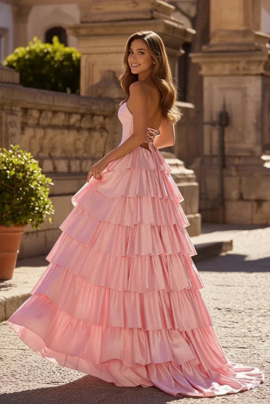 Woman in pink tiered A-line prom dress with sweetheart neckline and keyhole back outdoors