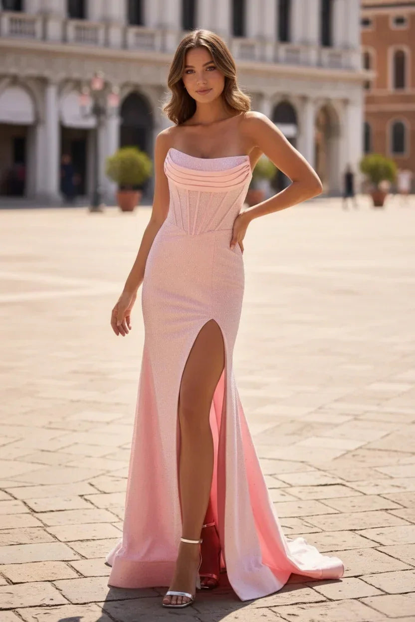 Woman in a pink strapless mermaid prom dress with beaded corset bodice and thigh-high slit