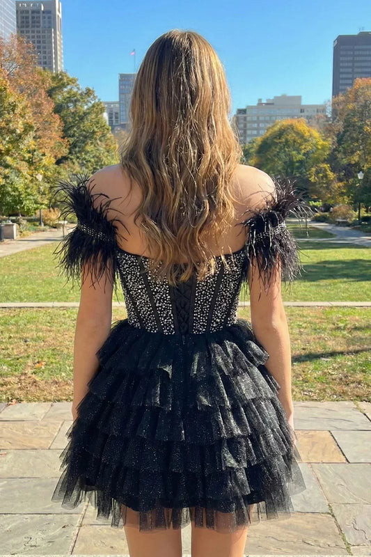 Woman outdoors in a black off-the-shoulder beaded homecoming dress with feathers and ruffles