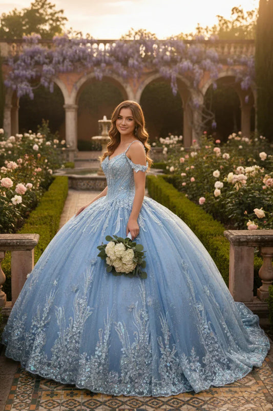 Young woman in blue off-the-shoulder lace ball gown with floral embroidery, standing in a garden holding white bouquet.