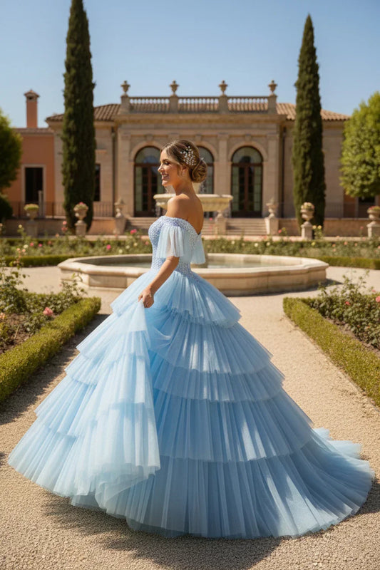 Woman in elegant blue off-the-shoulder layered ruffle quinceanera gown outdoors