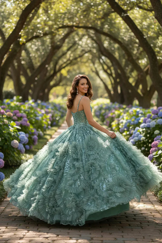 Woman in a green textured ruffle ball gown with glitter, posing outdoors among blooming hydrangeas.