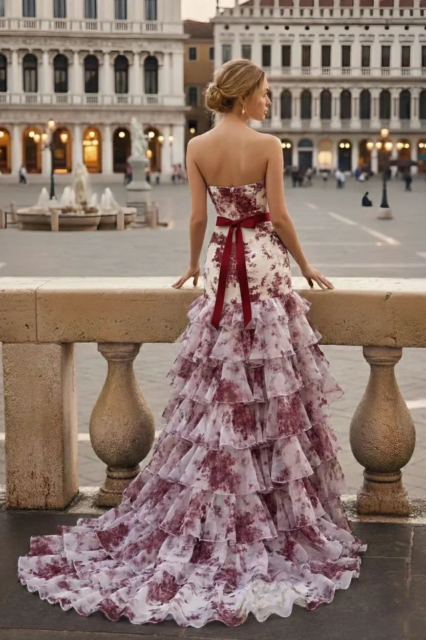Strapless floral tiered mermaid prom dress with ruffles and ribbon bow, outdoor plaza