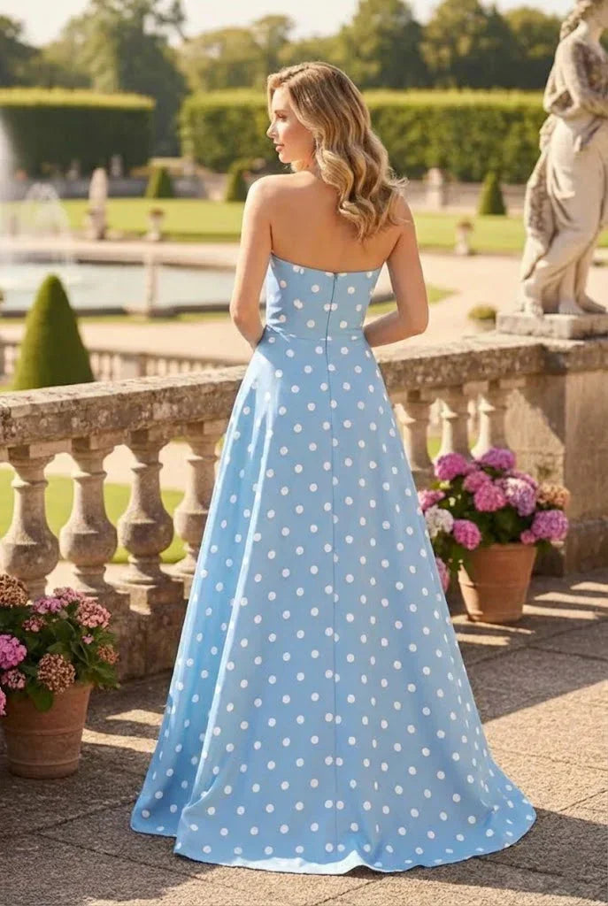 Woman in strapless blue polka dot A-line prom dress outdoors in garden setting