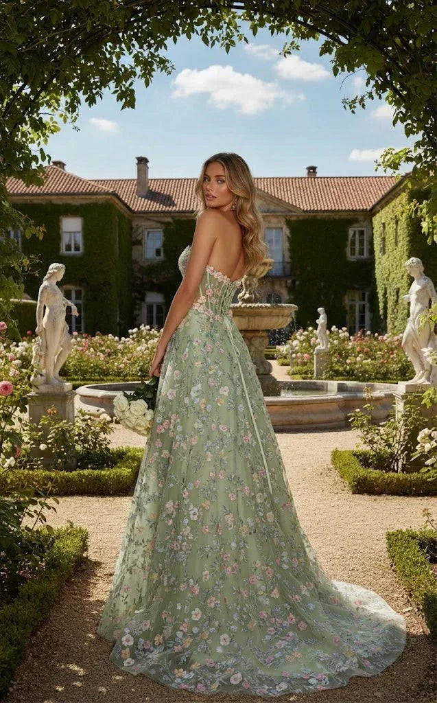 Woman in a green strapless floral applique A-line gown standing in a garden with statues.