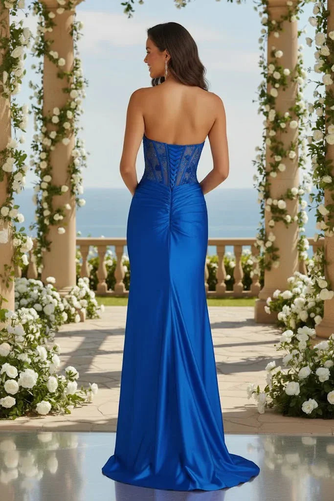 Woman in royal blue strapless satin mermaid prom dress with corset back and lace details, garden setting