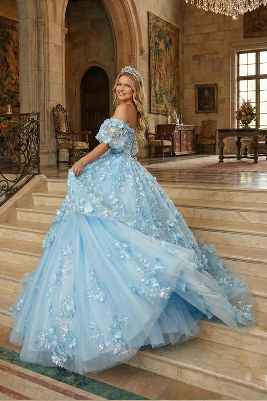 Woman in blue V-neck ball gown with textured ruffles, 3D floral details, and tiara on staircase