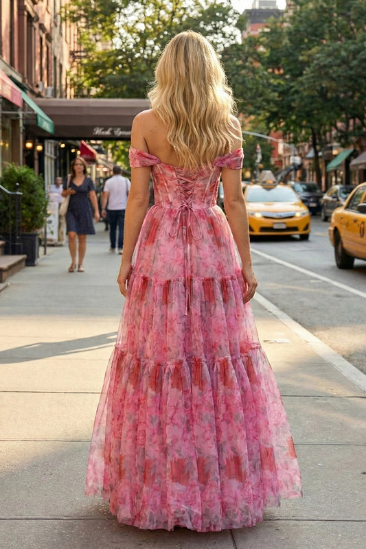 Back view of Sevoba pink rose print tulle evening gown showing a lace-up corset back and tiered ruffle skirt, street background