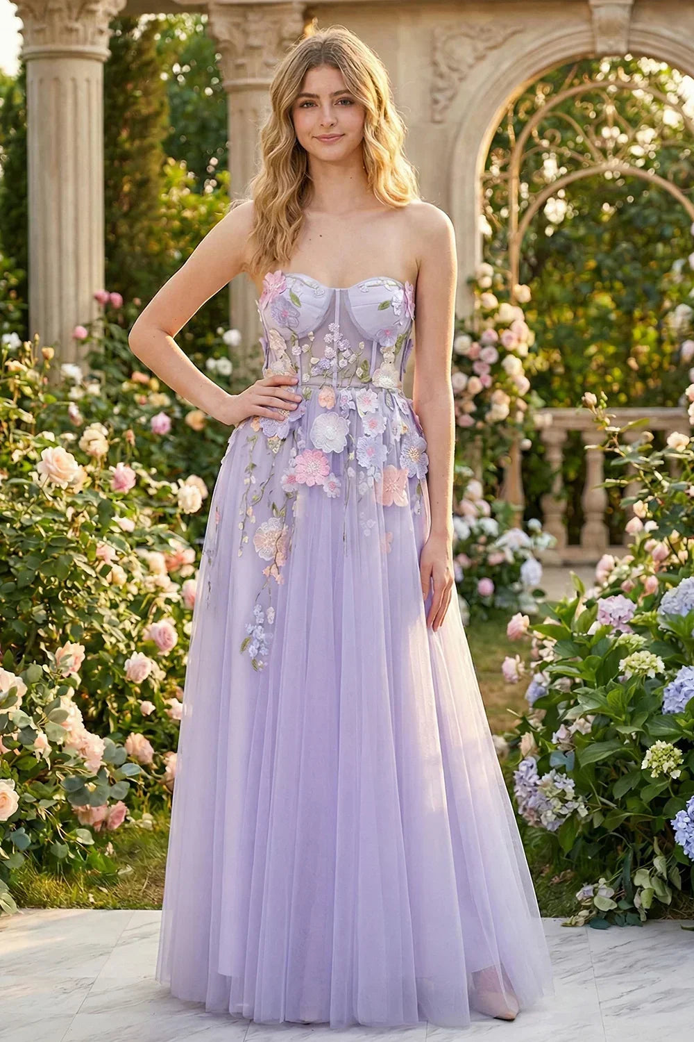 Sevoba strapless lilac tulle prom dress featuring colorful 3D floral appliqués and a sheer corset bodice, front view in garden setting
