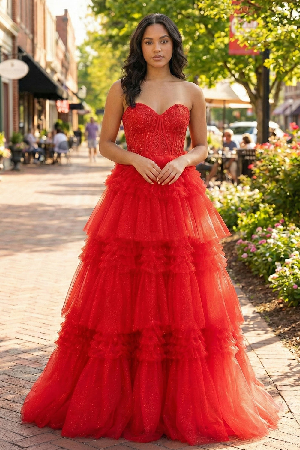 Sevoba strapless red tiered tulle prom dress featuring a beaded corset bodice and voluminous ruffle layers, front view in outdoor street setting
