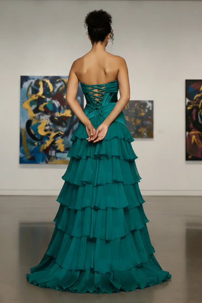 Woman in a strapless teal tiered evening gown with lace-up back standing in art gallery