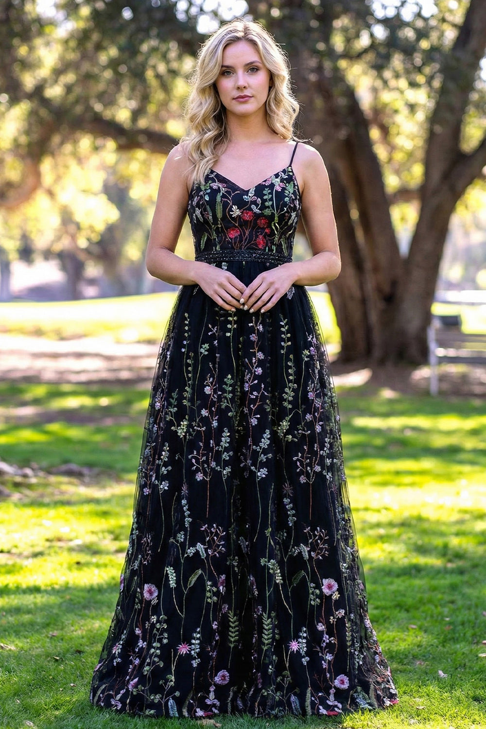 Sevoba black tulle A-line prom dress featuring colorful wildflower embroidery, a V-neckline, and a beaded waist belt, front view in outdoor park setting