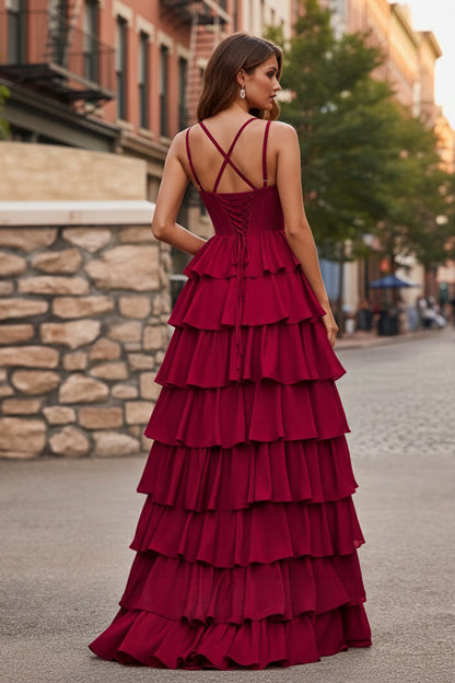 Back view of Sevoba wine red evening gown showing a lace-up corset back, criss-cross straps, and voluminous layered ruffle skirt, street background