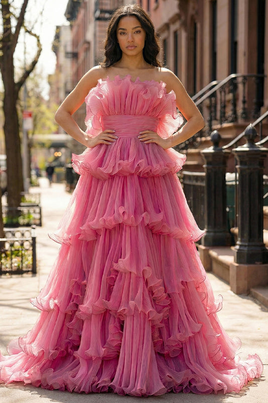 Sevoba strapless pink pleated tulle prom dress featuring a voluminous tiered ruffle skirt and ruched waistband, front view in urban street setting.