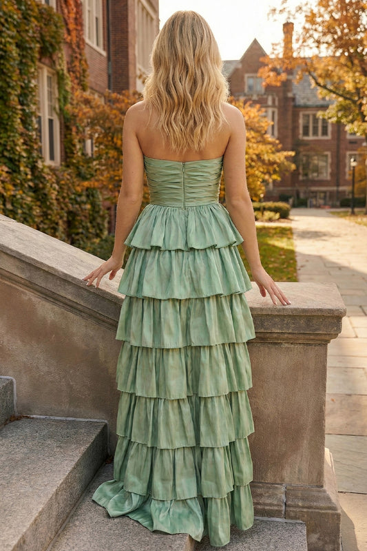 Back view of Sevoba sage green evening gown showing a zipper closure and voluminous tiered ruffle skirt, outdoor campus background