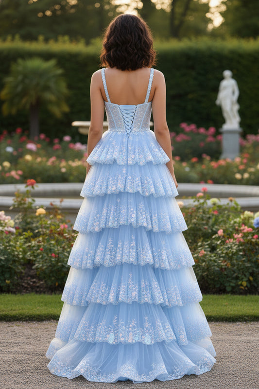 Back view of Sevoba light blue floral embroidered prom dress showing a lace-up corset back and tiered tulle skirt, garden background