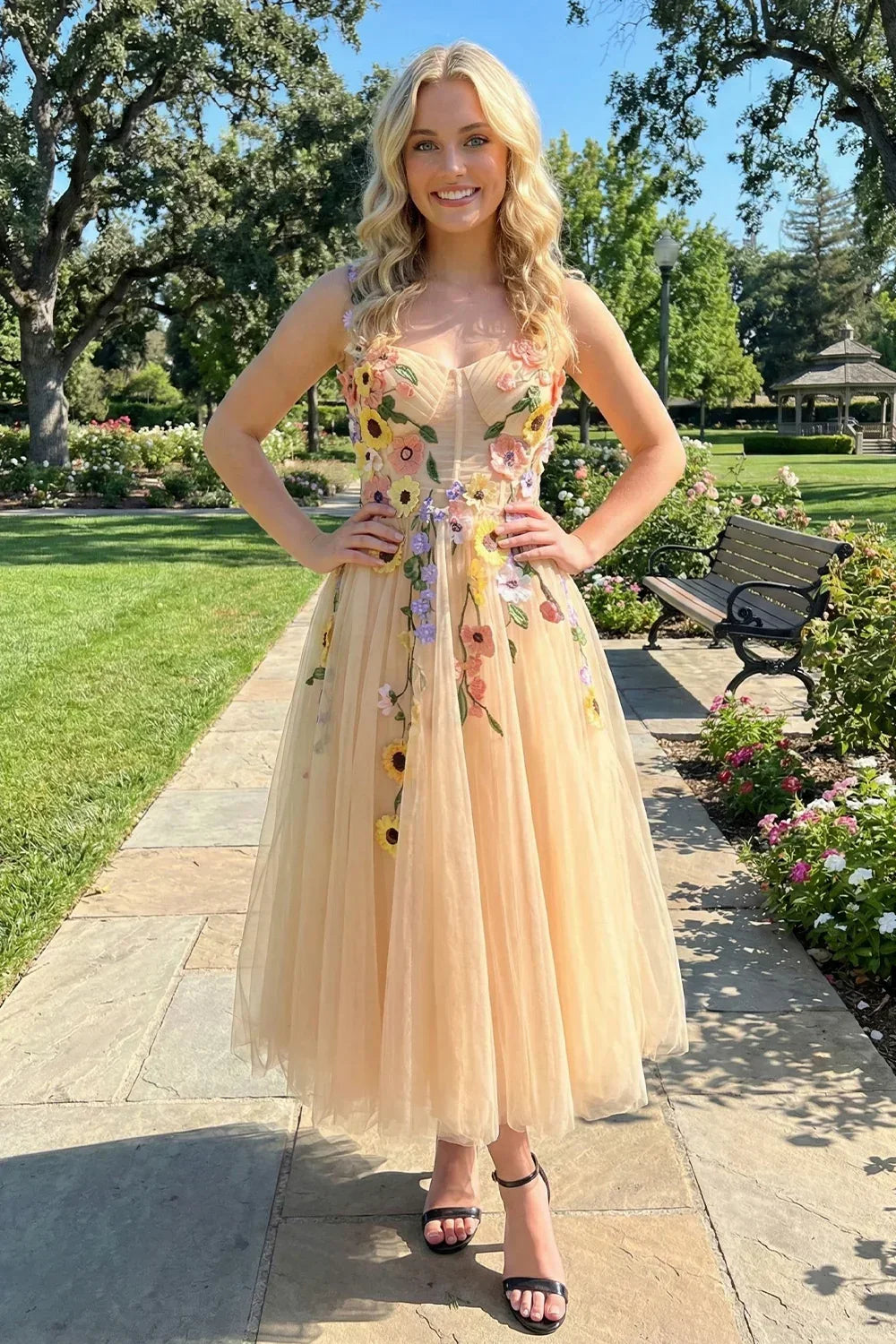 Woman in a 3D floral tulle ankle-length prom dress posing outdoors in a garden