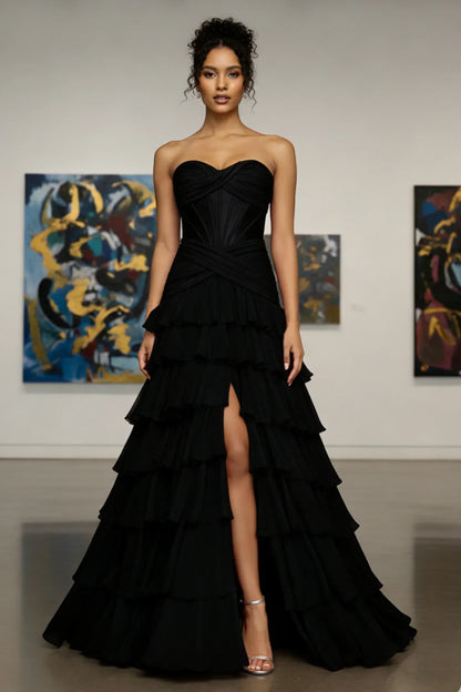 Woman in a strapless black ruffle evening gown with front slit, standing in art gallery.