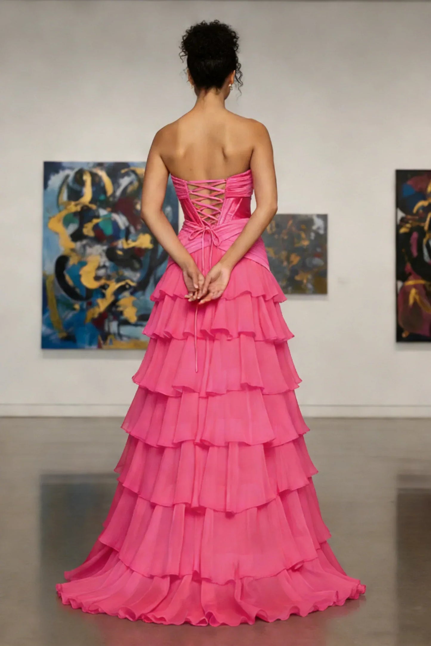 Back view of woman in strapless pink tiered ruffle gown, ideal for prom or formal events